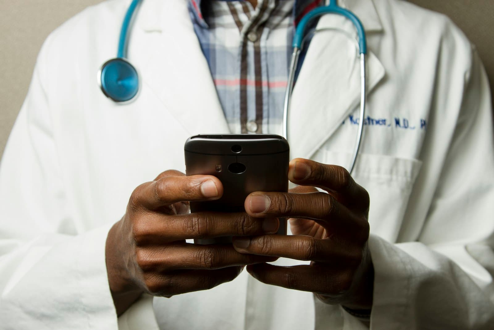 A clinician in a gown using a phone
