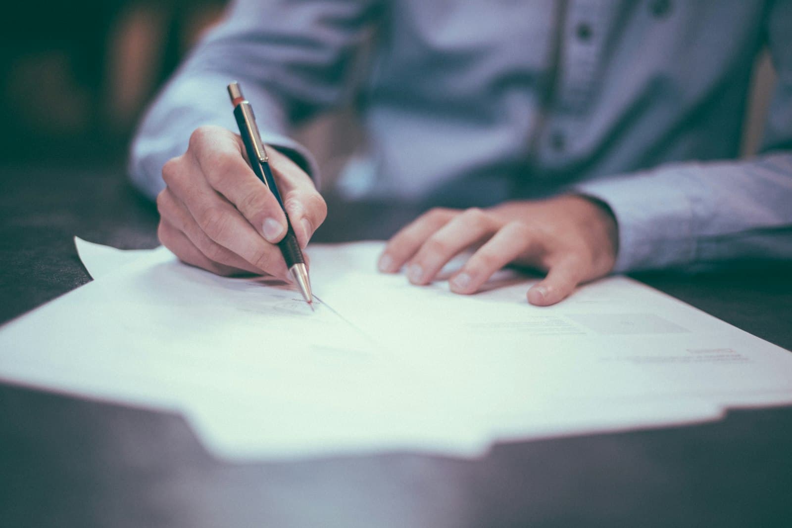 Person signing documents at a desk